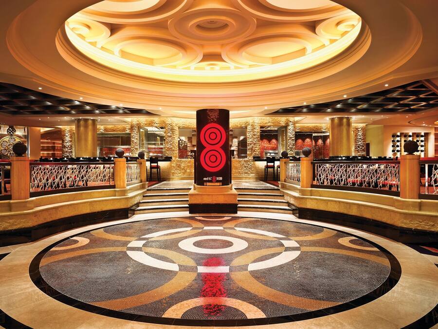 A spacious lobby with a circular patterned floor, a central pillar with a red logo, and a ceiling with a circular design.