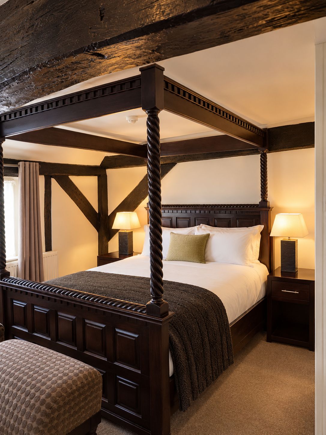 A four-poster bed with a dark wooden frame and a textured bedspread.
