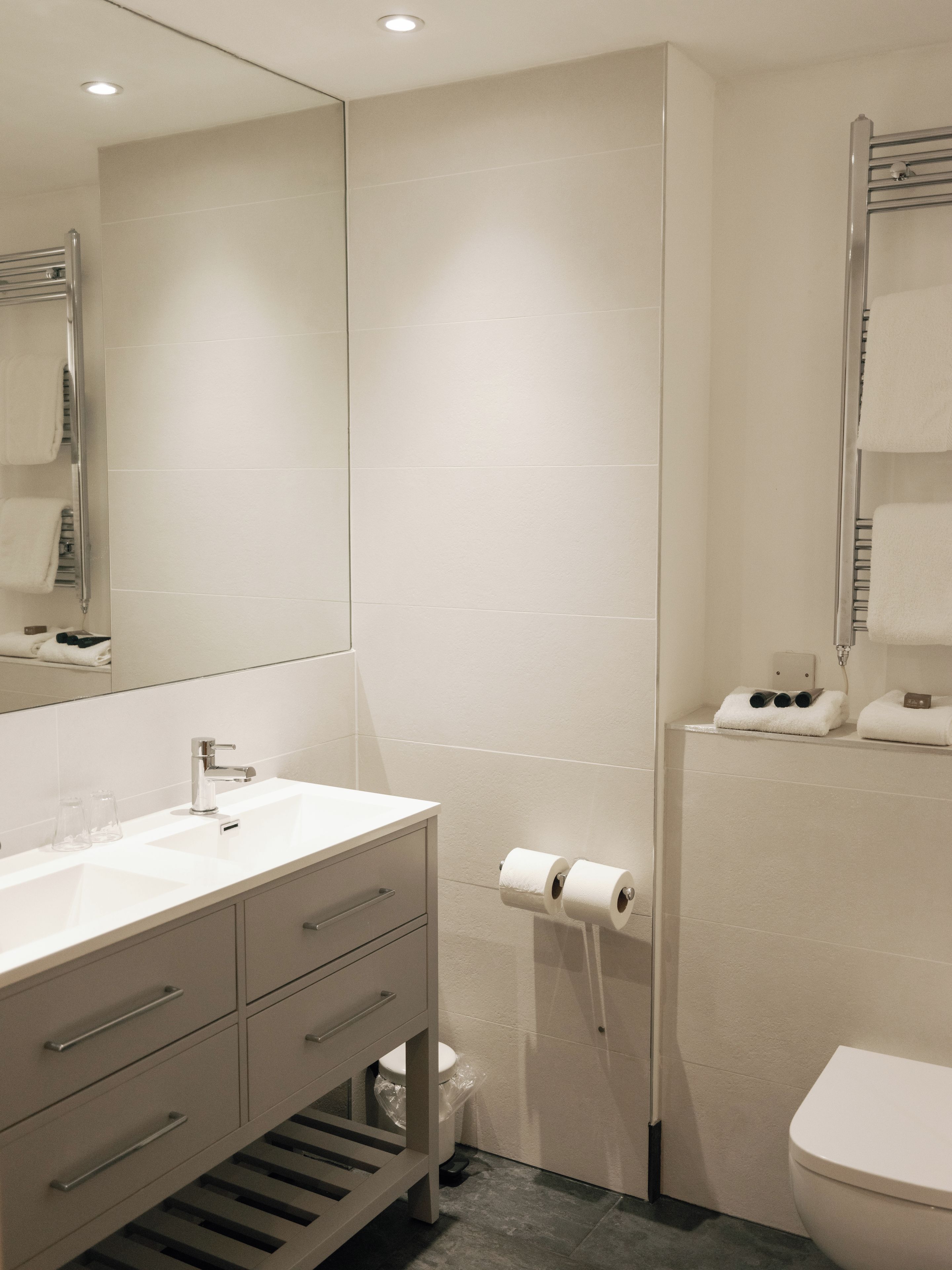 A modern bathroom with a white sink, mirror, and toilet.