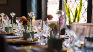A dining table set with glassware, plates, and floral centerpieces. - The Kings Arms Hotel (Amersham)