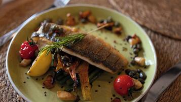 Une assiette de nourriture comprenant du poisson, des légumes et une garniture.