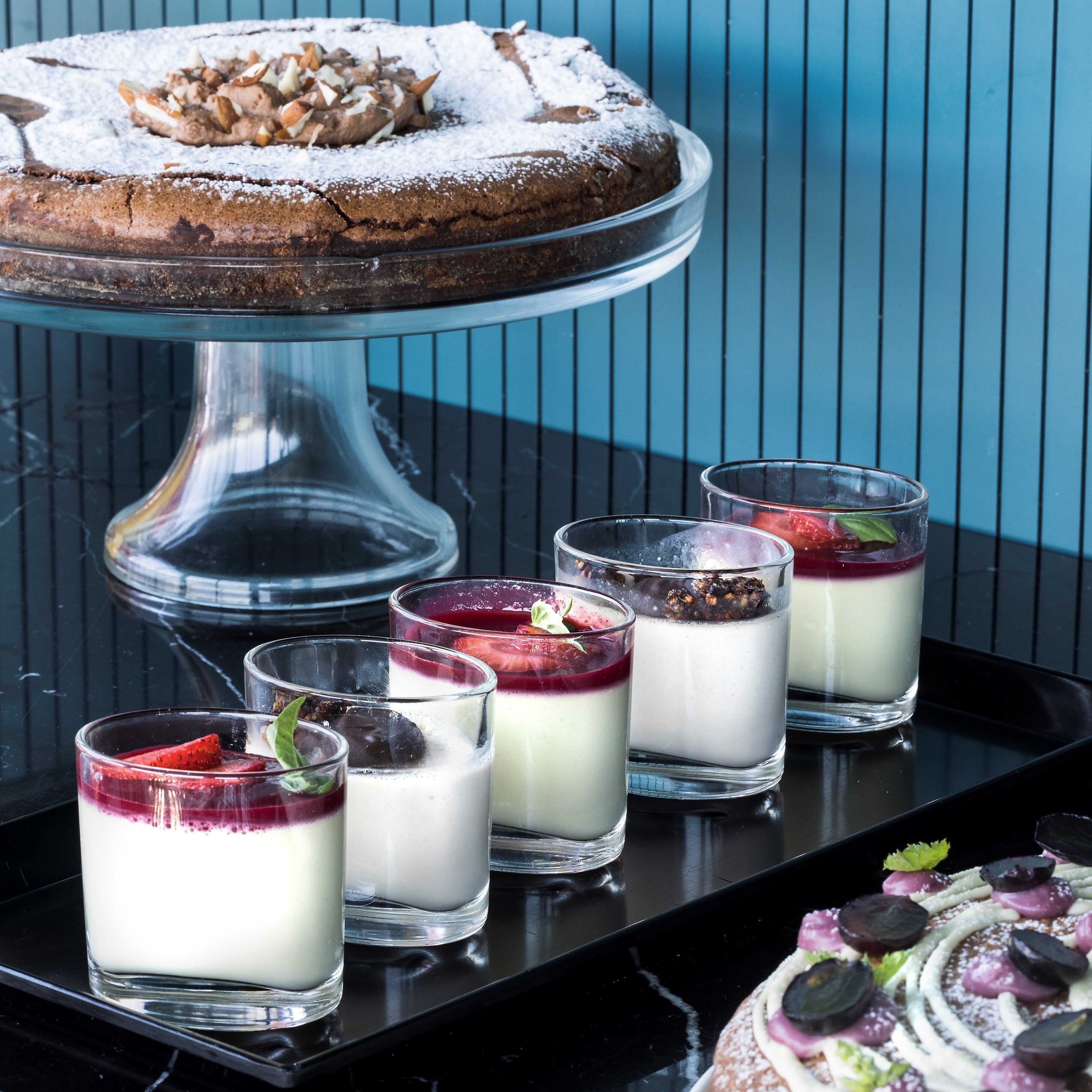 Et dessertbord med en kage på et fad og fire glas med lagkagedesserter.