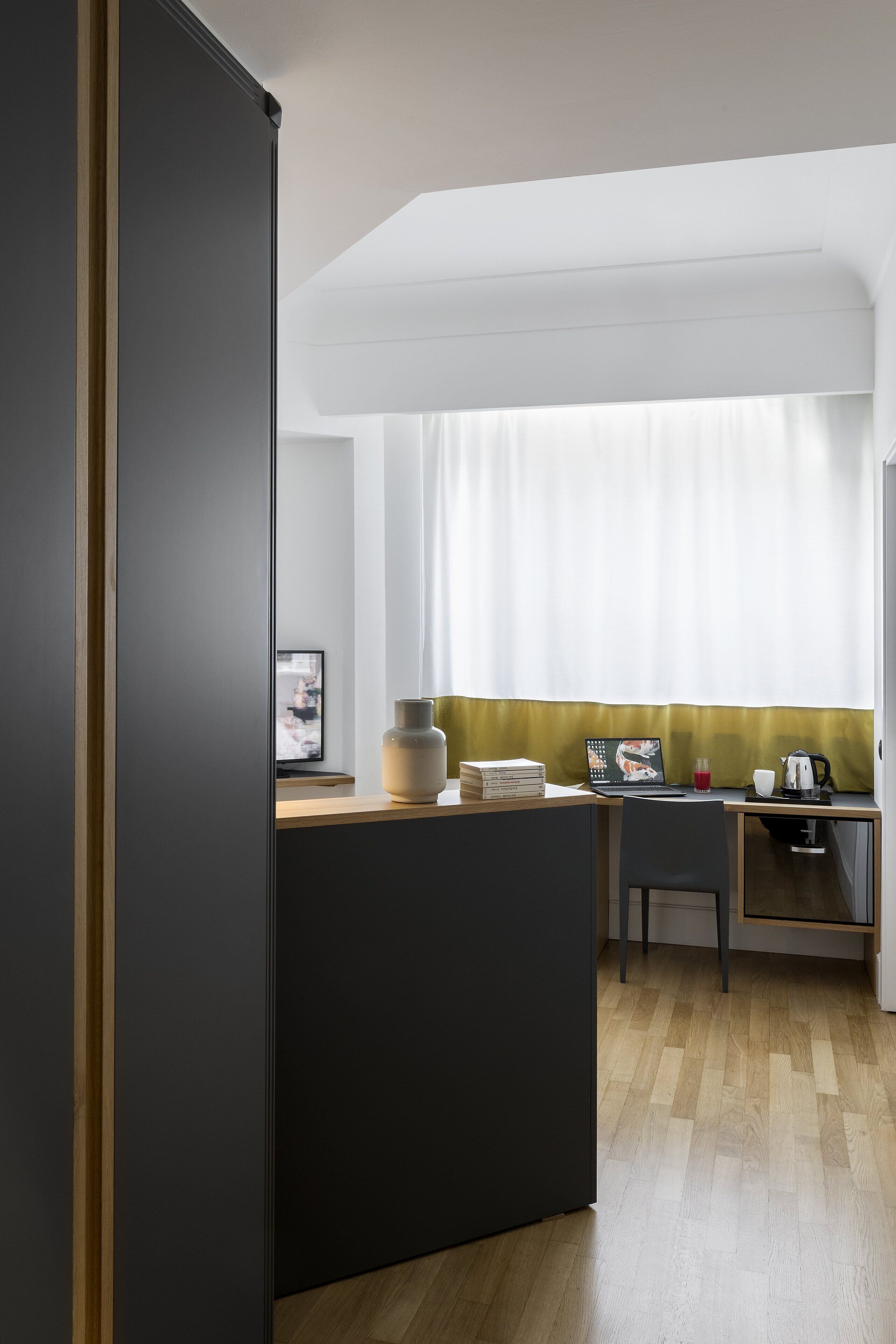 Una cocina moderna con encimera de madera, una isla negra y un área de comedor con una silla y una mesa.