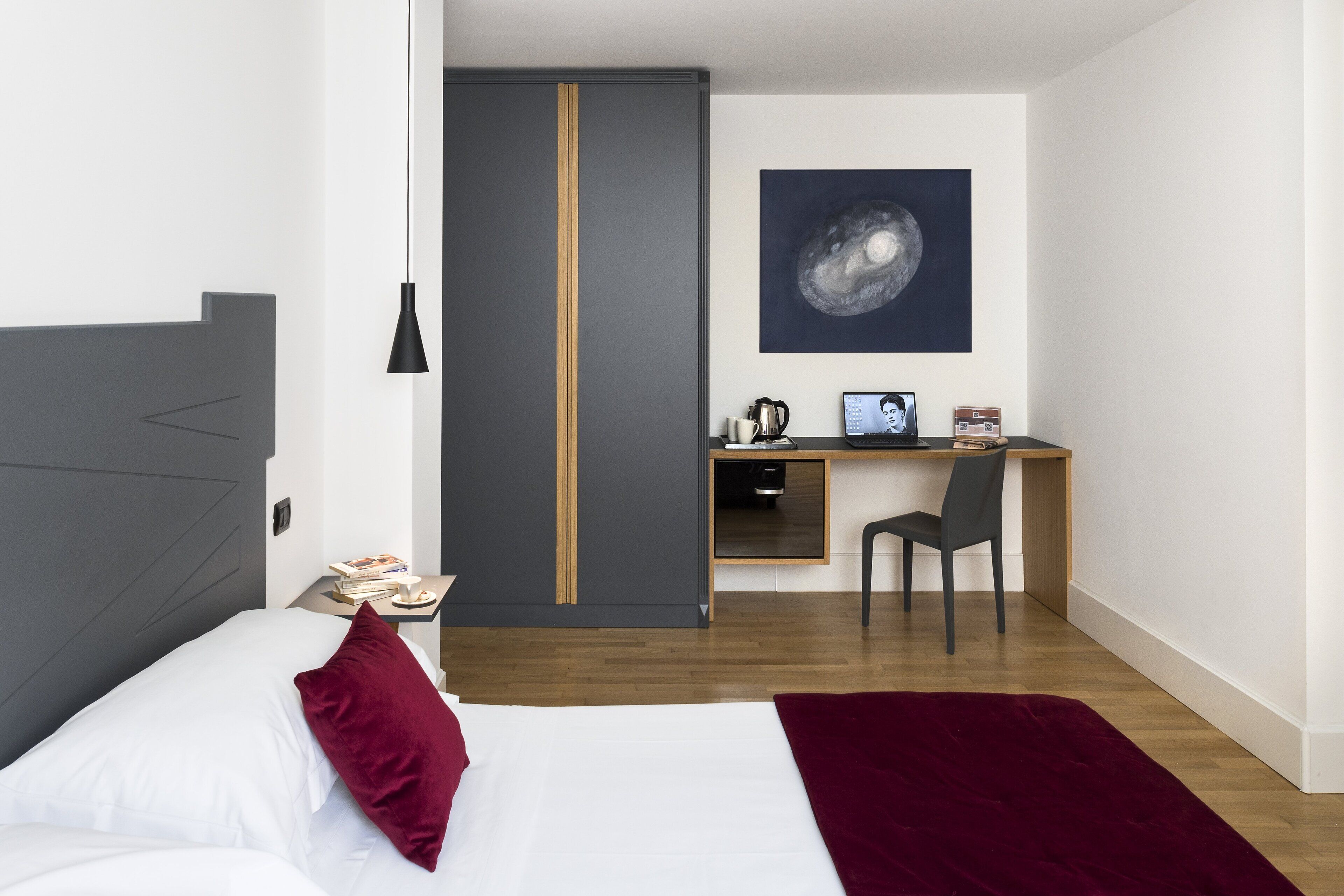 Une chambre d’hôtel moderne équipée d’un lit, d’un bureau, d’une chaise et d’une grande œuvre d’art accrochée au mur.