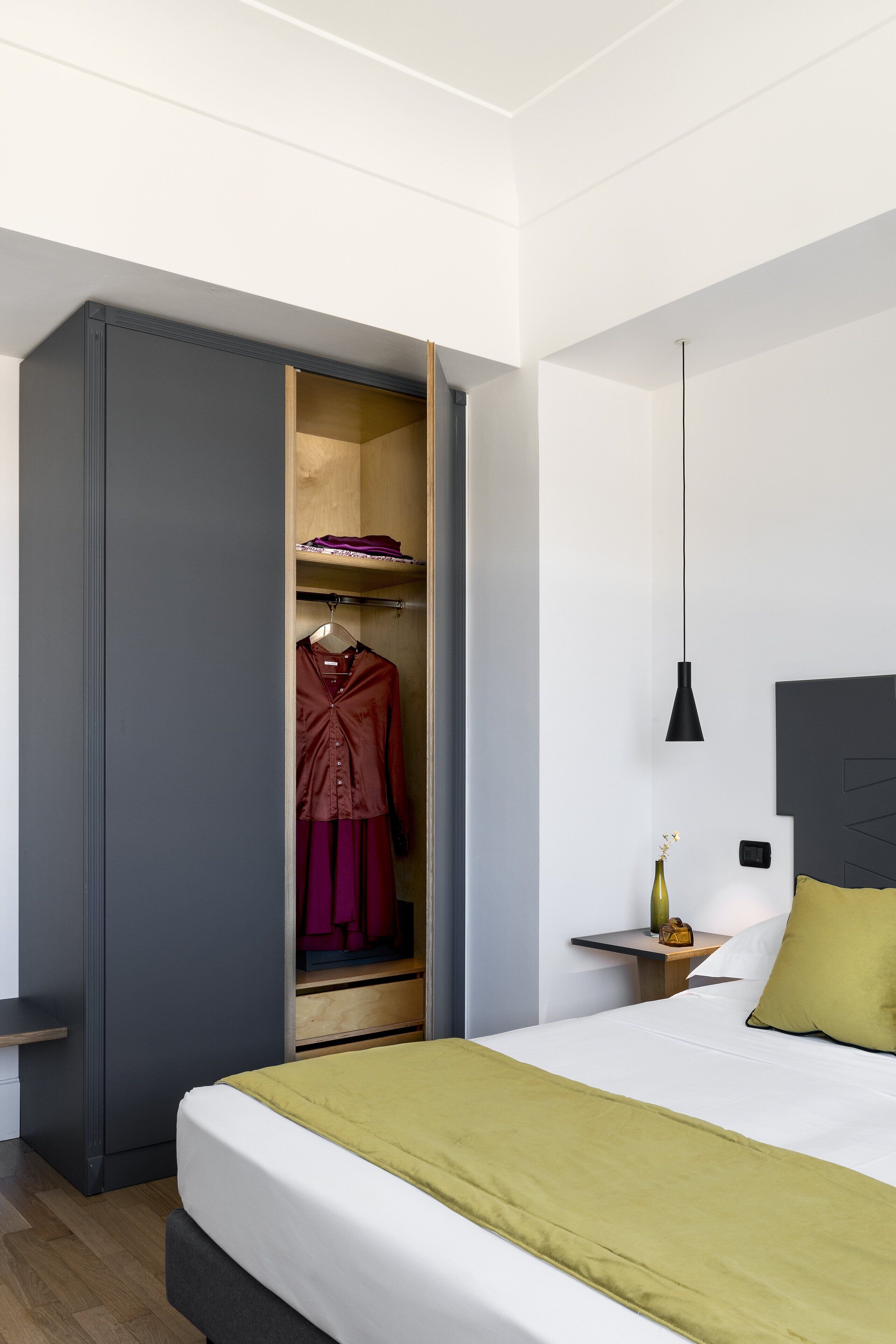 Una camera da letto con un letto, un armadio, un comodino e una lampada a sospensione.