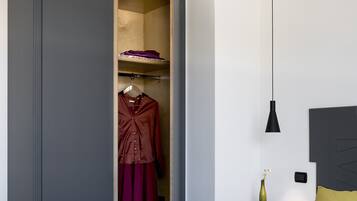 Una camera da letto con un letto, un armadio, un comodino e una lampada a sospensione.