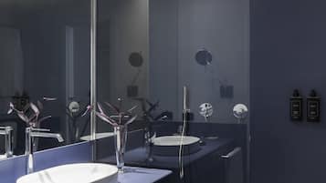 A modern bathroom with a large mirror, a round sink, and a showerhead.