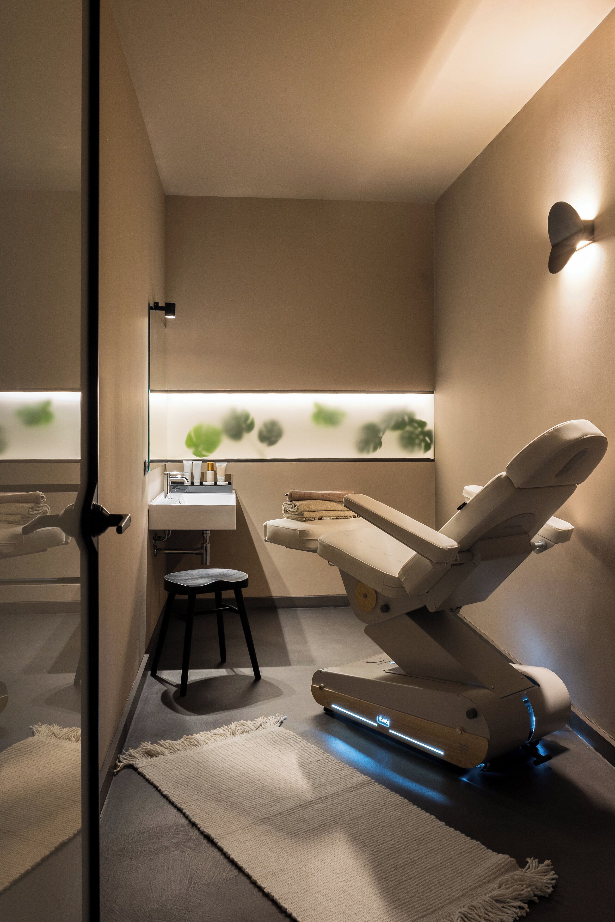 Una moderna clinica dentistica con una poltrona reclinabile, un lavandino e uno specchio.