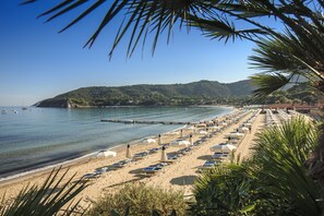 Aan een privéstrand, wit zand, ligstoelen, parasols