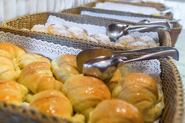 A display of various pastries in wicker baskets with silver spoons.