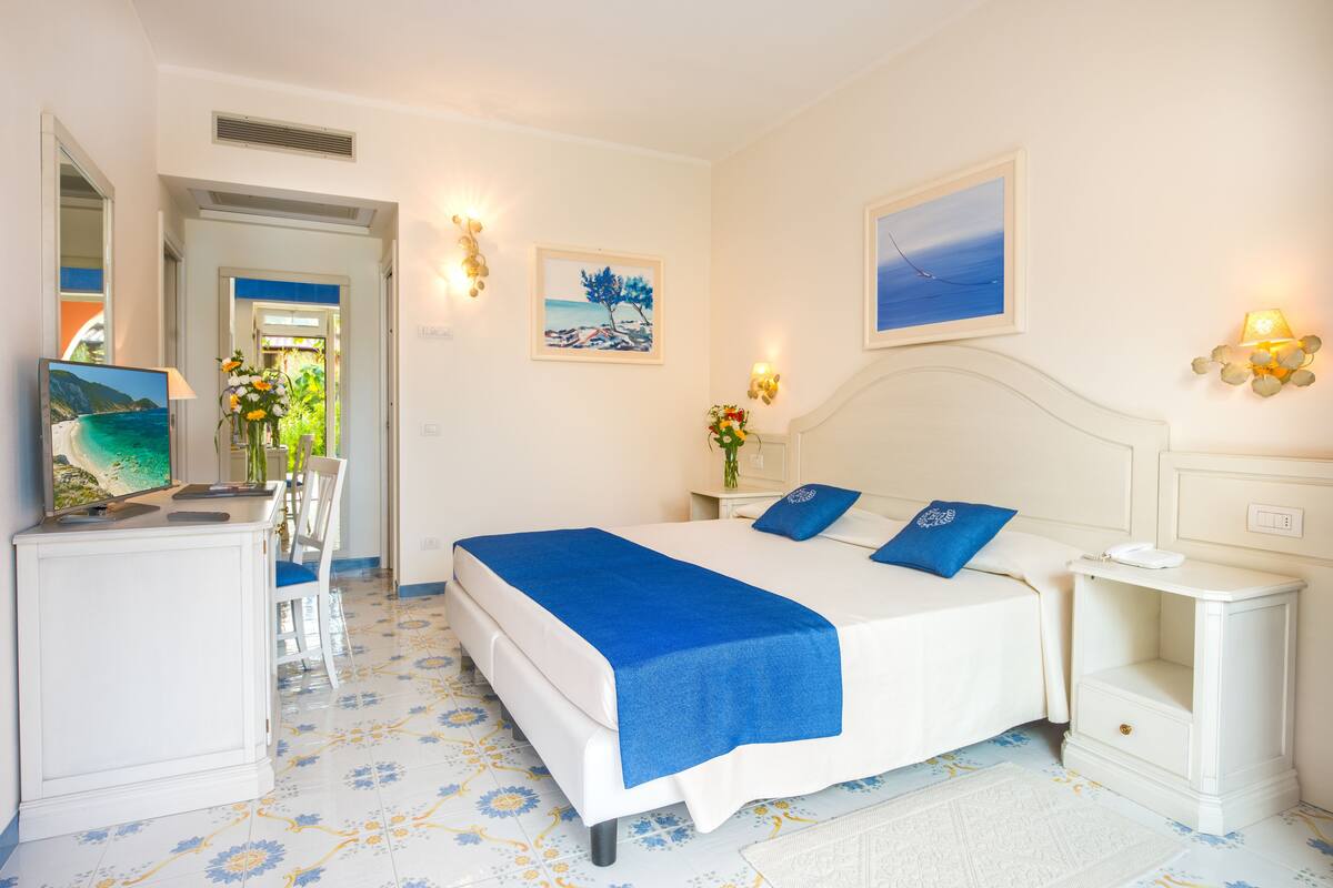 A bedroom with a bed, bedside table, and a desk with a chair.