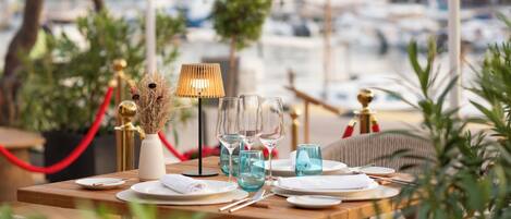 A table set for dining with a view of boats in the background.