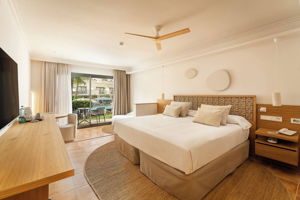 A hotel room with a large bed, a desk, and a view of the outdoors.