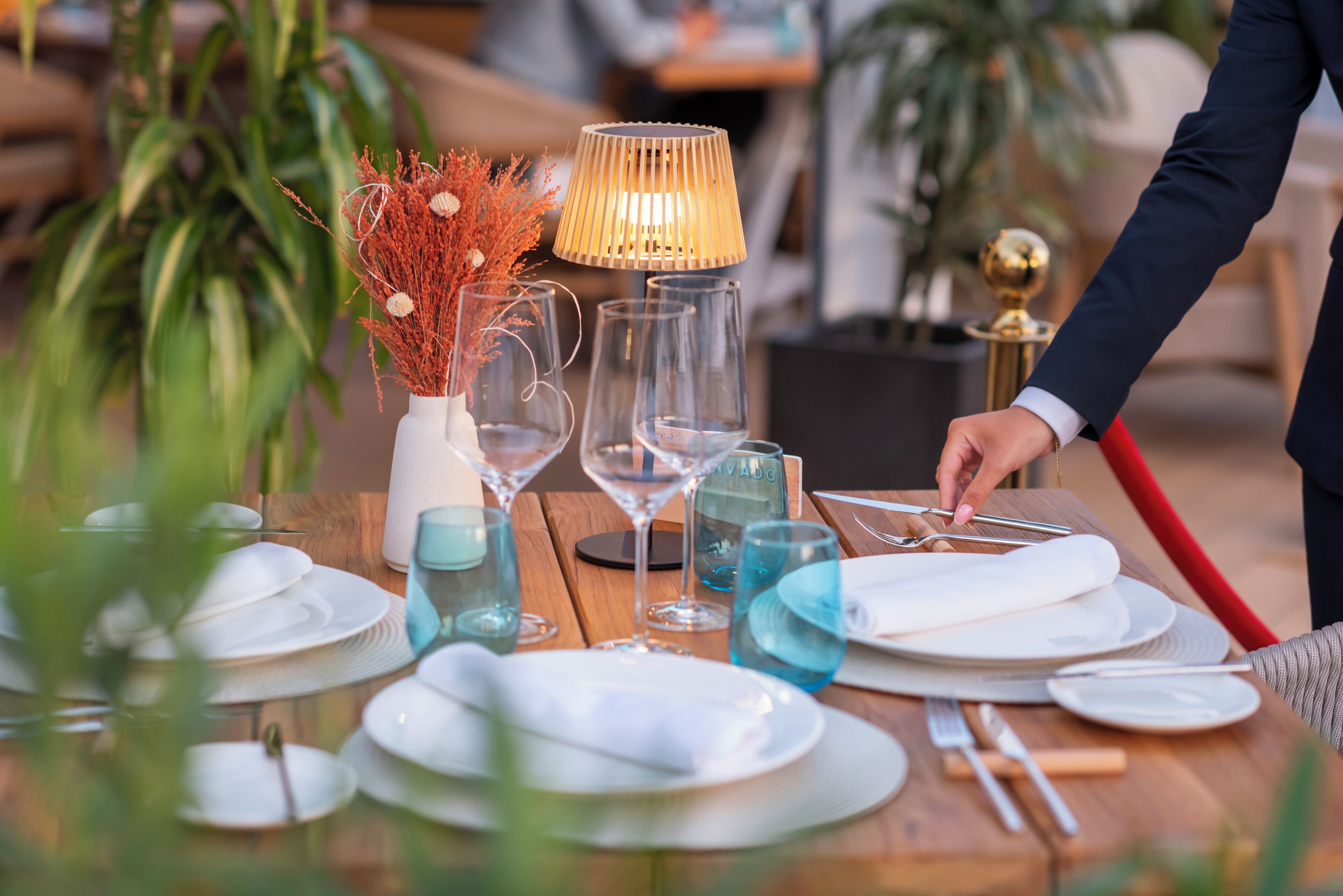 A table set with plates, glasses, and a lamp, indicating a dining area.