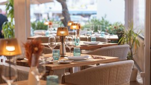 Un restaurante con mesas dispuestas para comer, con lámparas, platos y vasos.