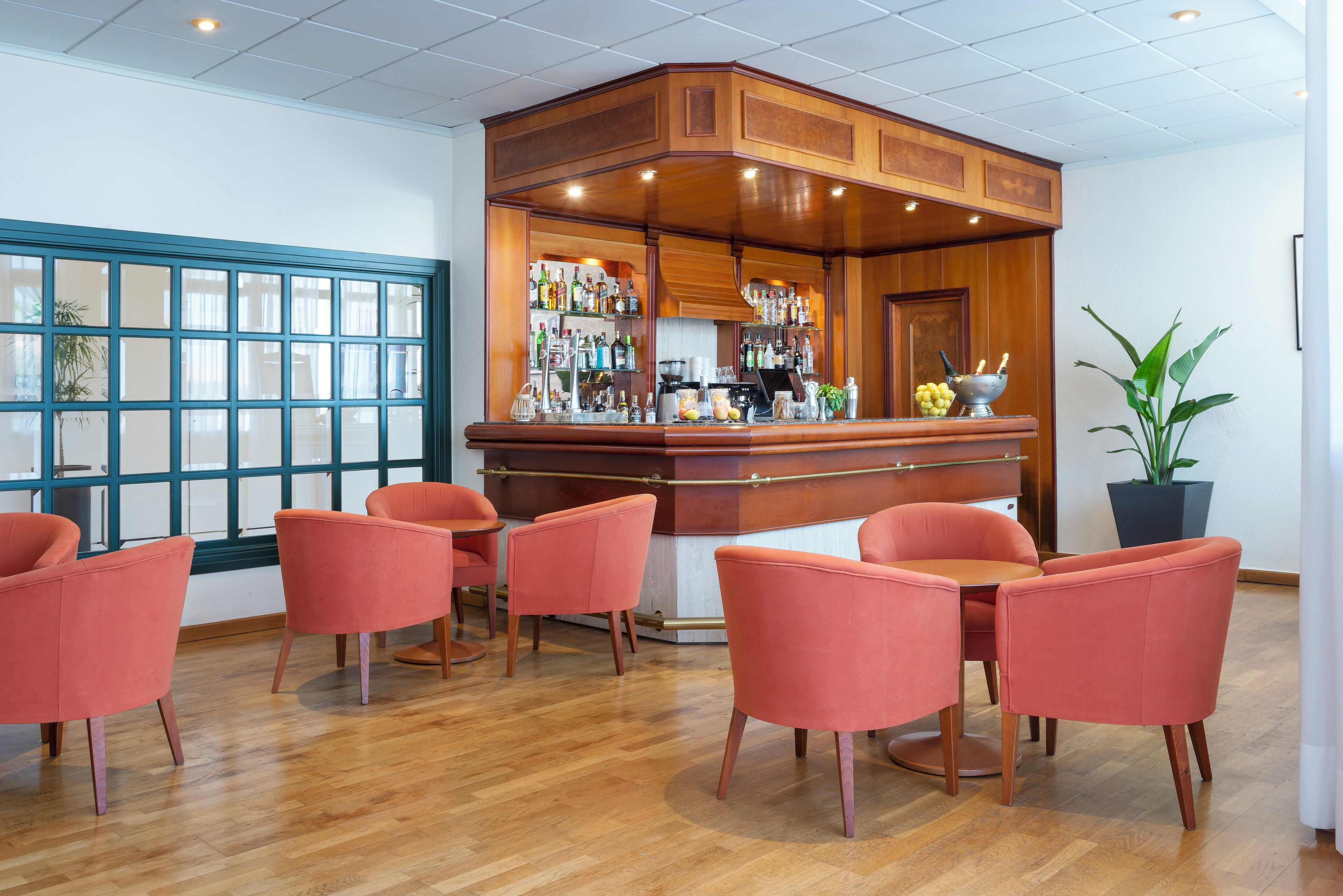 A bar area with wooden cabinetry, a bar counter, and a seating area with orange chairs.