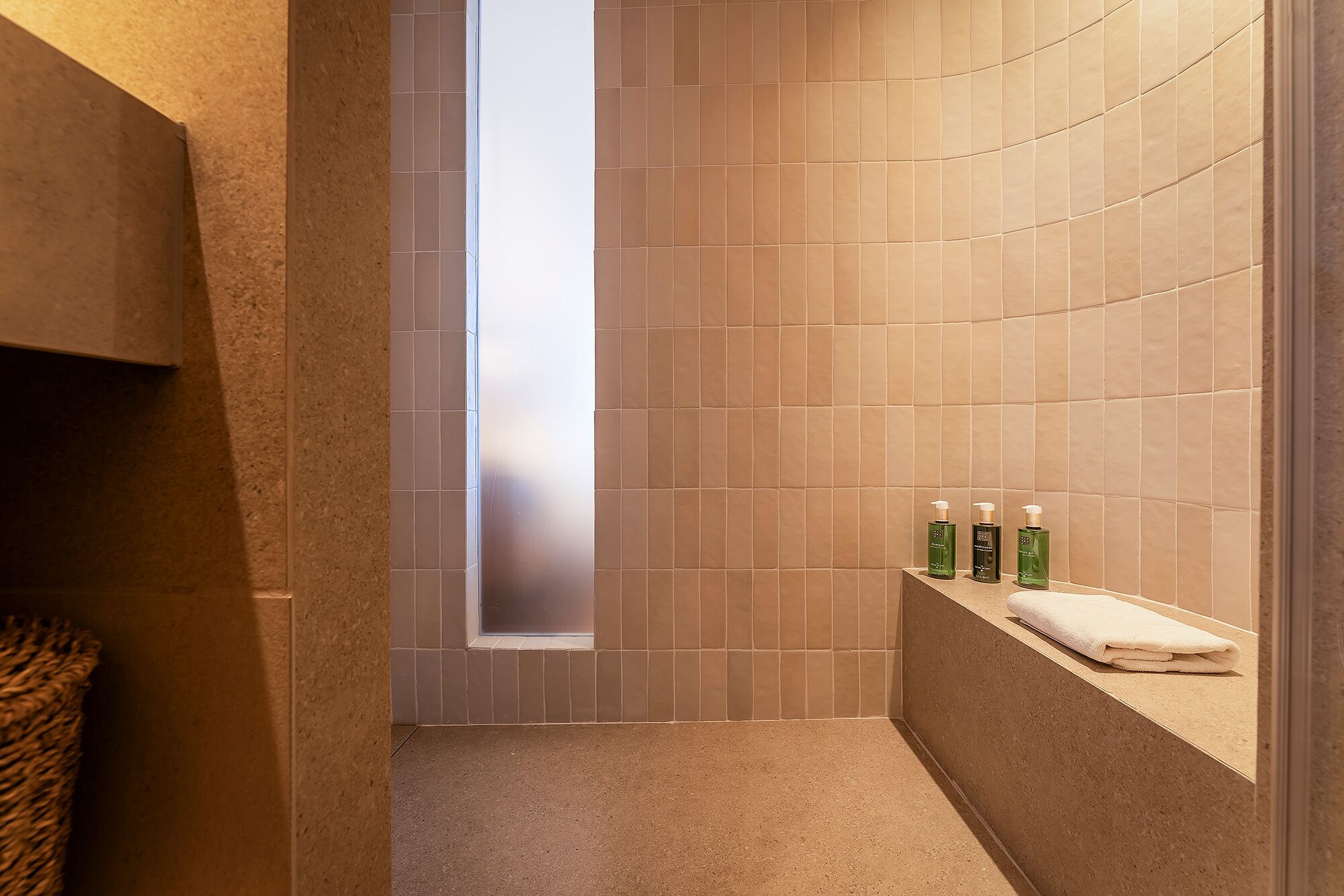 Un baño con pared curva, ventana y estante con artículos de aseo.