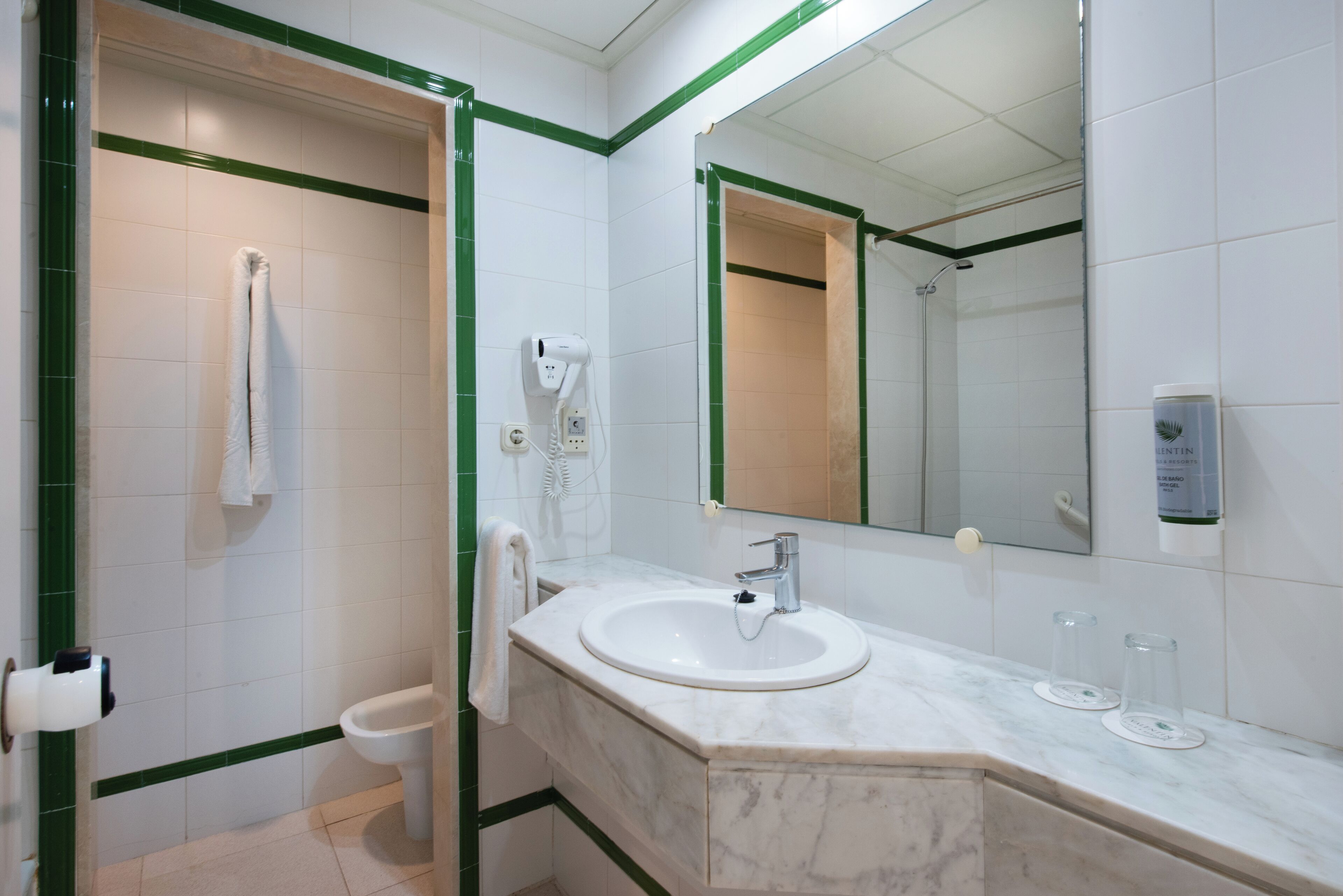 A bathroom with a white sink, a mirror, and a shower.
