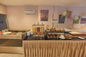 A buffet area with various food items, serving trays, and a decorative plant arrangement.
