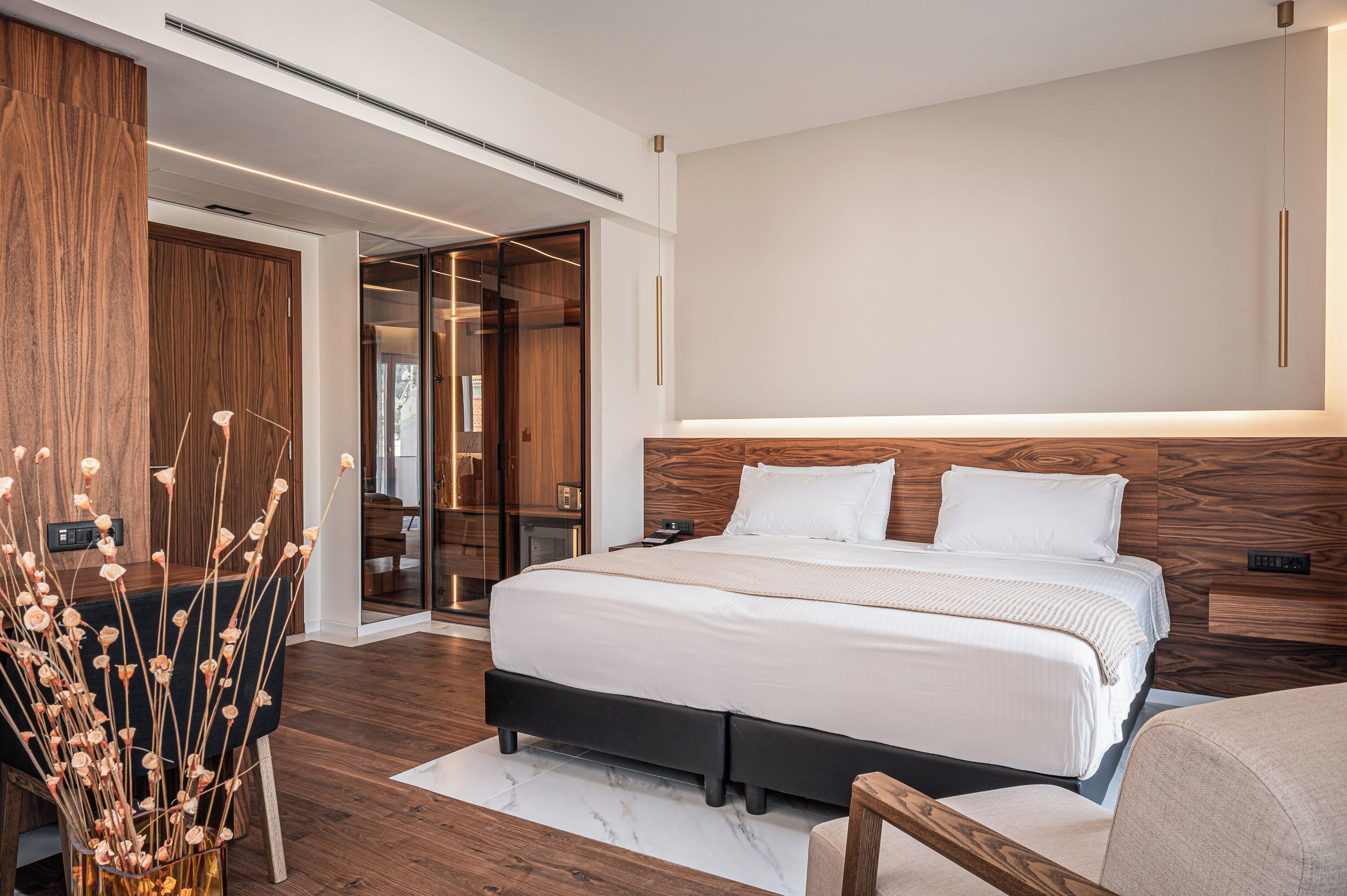 A modern bedroom with a large bed, wooden headboard, and a built-in wardrobe.