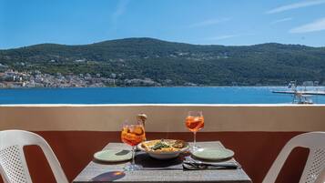 A table with a meal and drinks, overlooking a coastal town and hills.