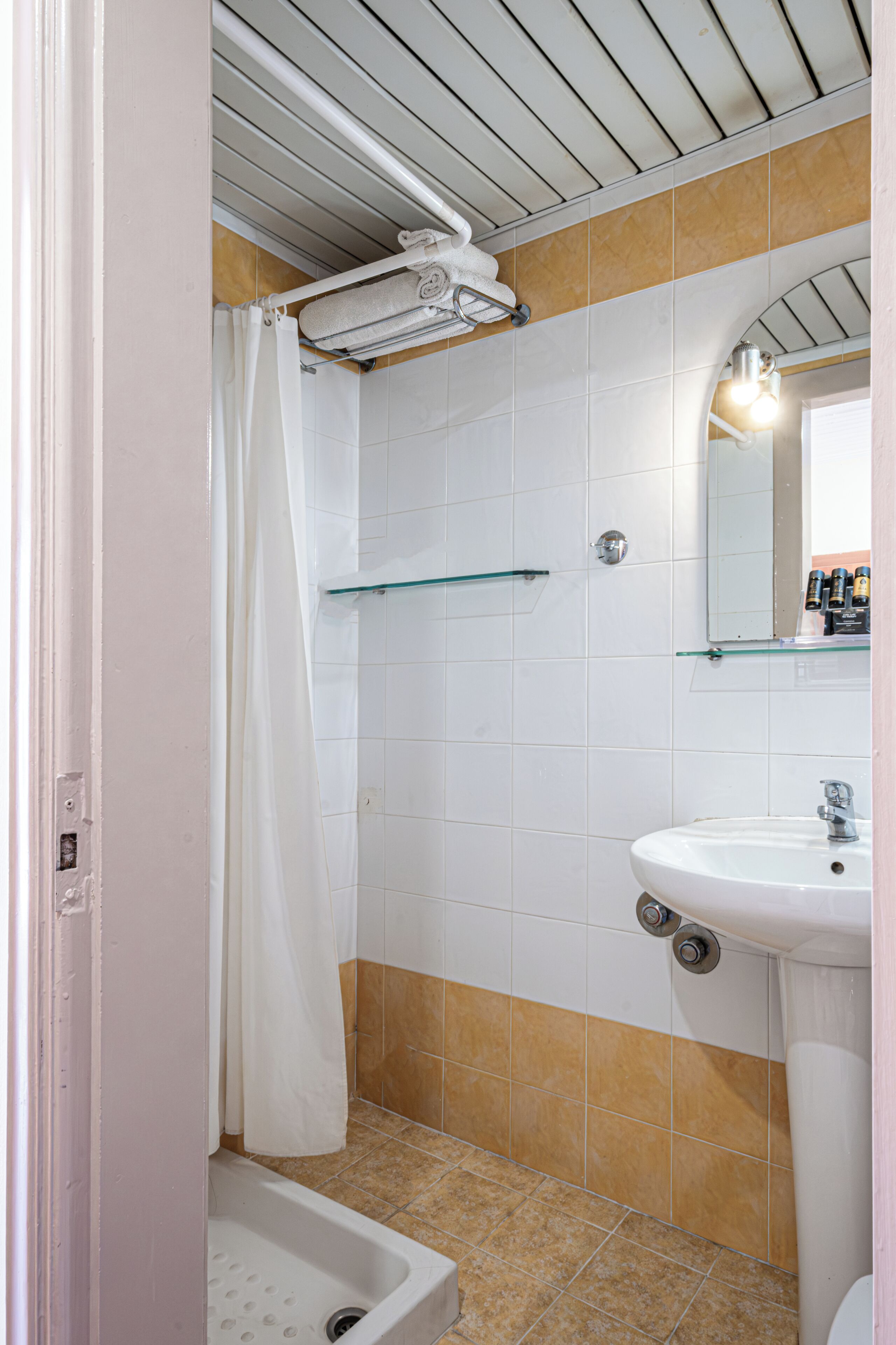 A bathroom with a shower, a sink, and a mirror.