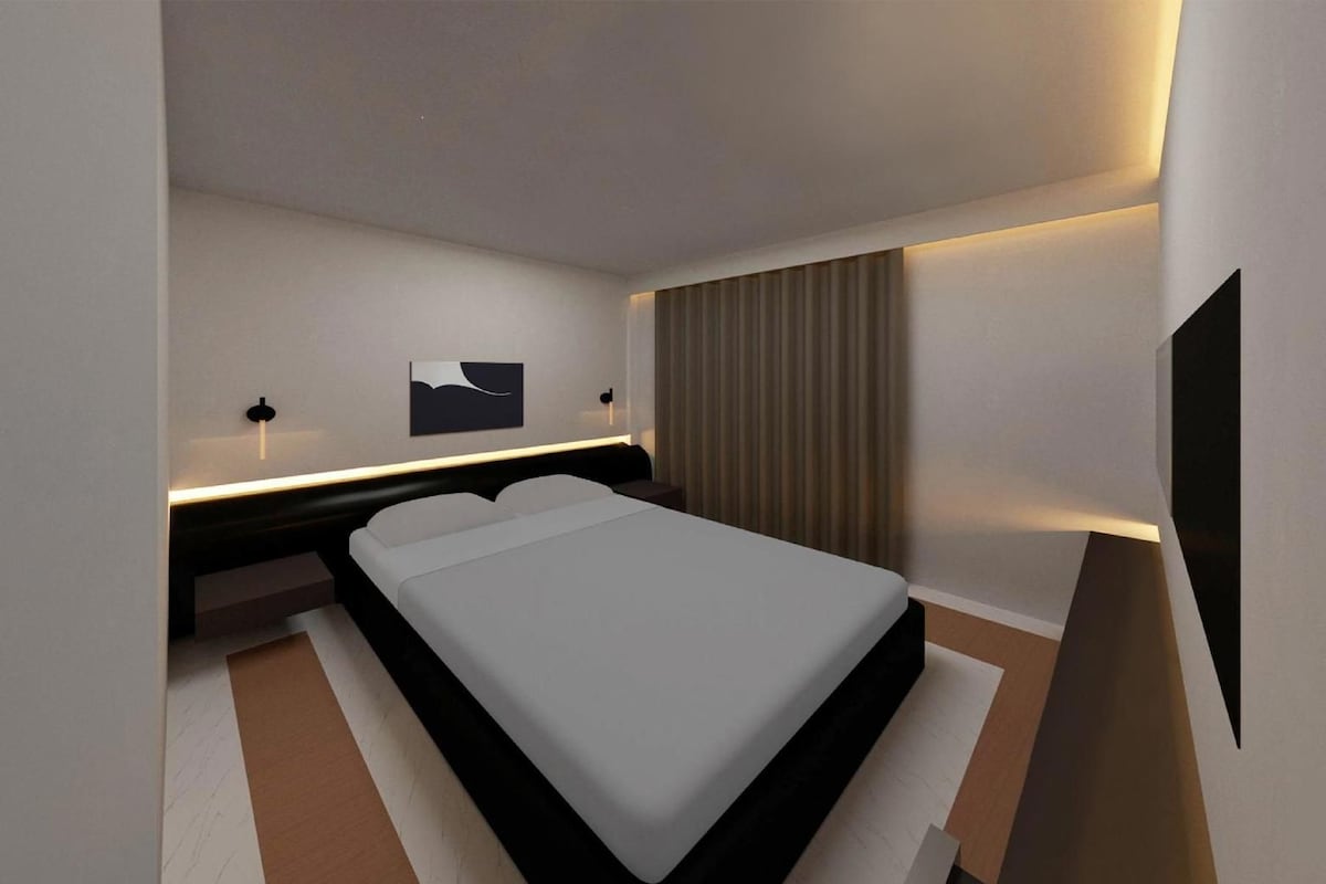 Ein modernes Hotelzimmer mit Bett, Nachttischen, einem an der Wand montierten Fernseher und einem Vorhang.