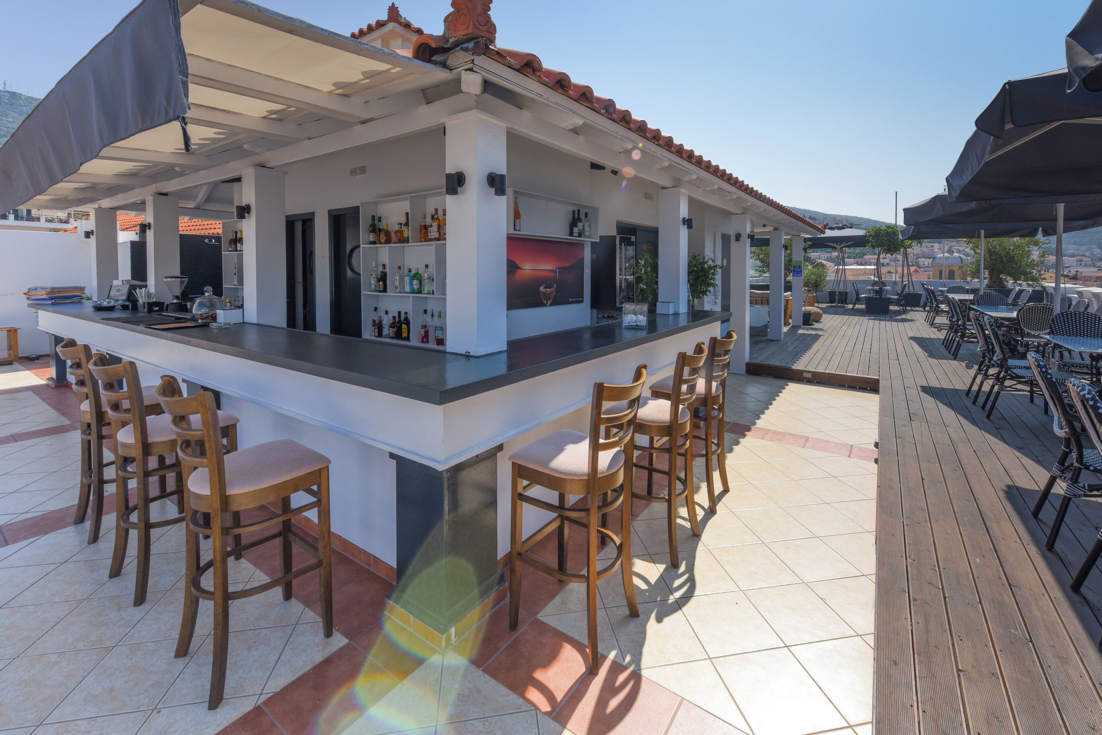 A bar area with a counter, bar stools, and a view of the landscape.