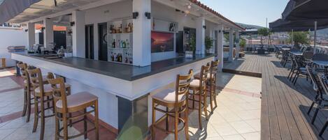A bar area with a counter, bar stools, and a view of the landscape.