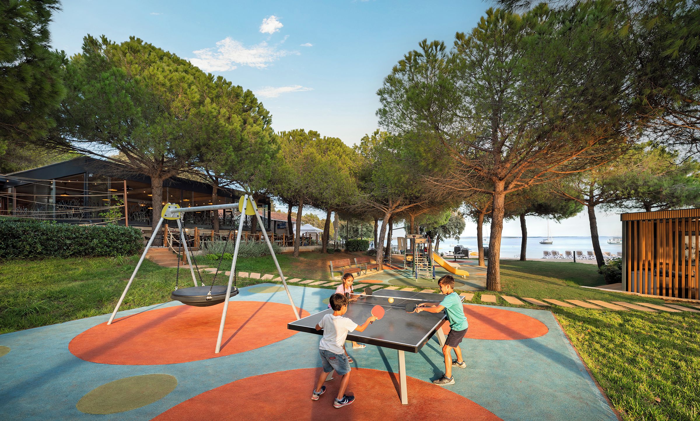Un área de juegos al aire libre con columpios, tobogán y mesa de ping pong.
