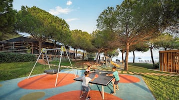 Un área de juegos al aire libre con columpios, tobogán y mesa de ping pong.