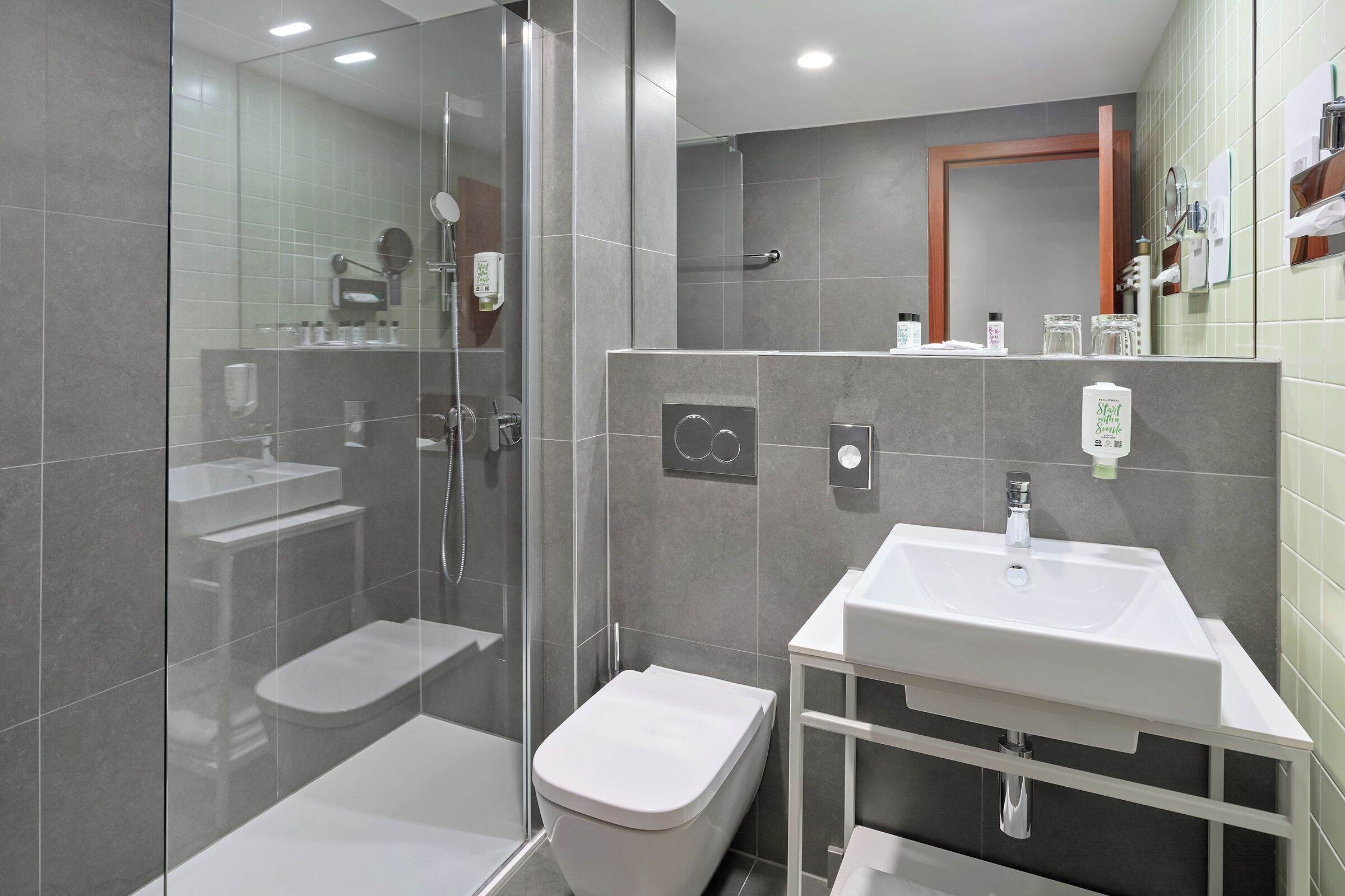A modern bathroom with a glass-enclosed shower, a toilet, and a sink with a mirror above it.