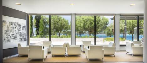 A modern waiting area with large windows, white chairs, and a minimalist design.