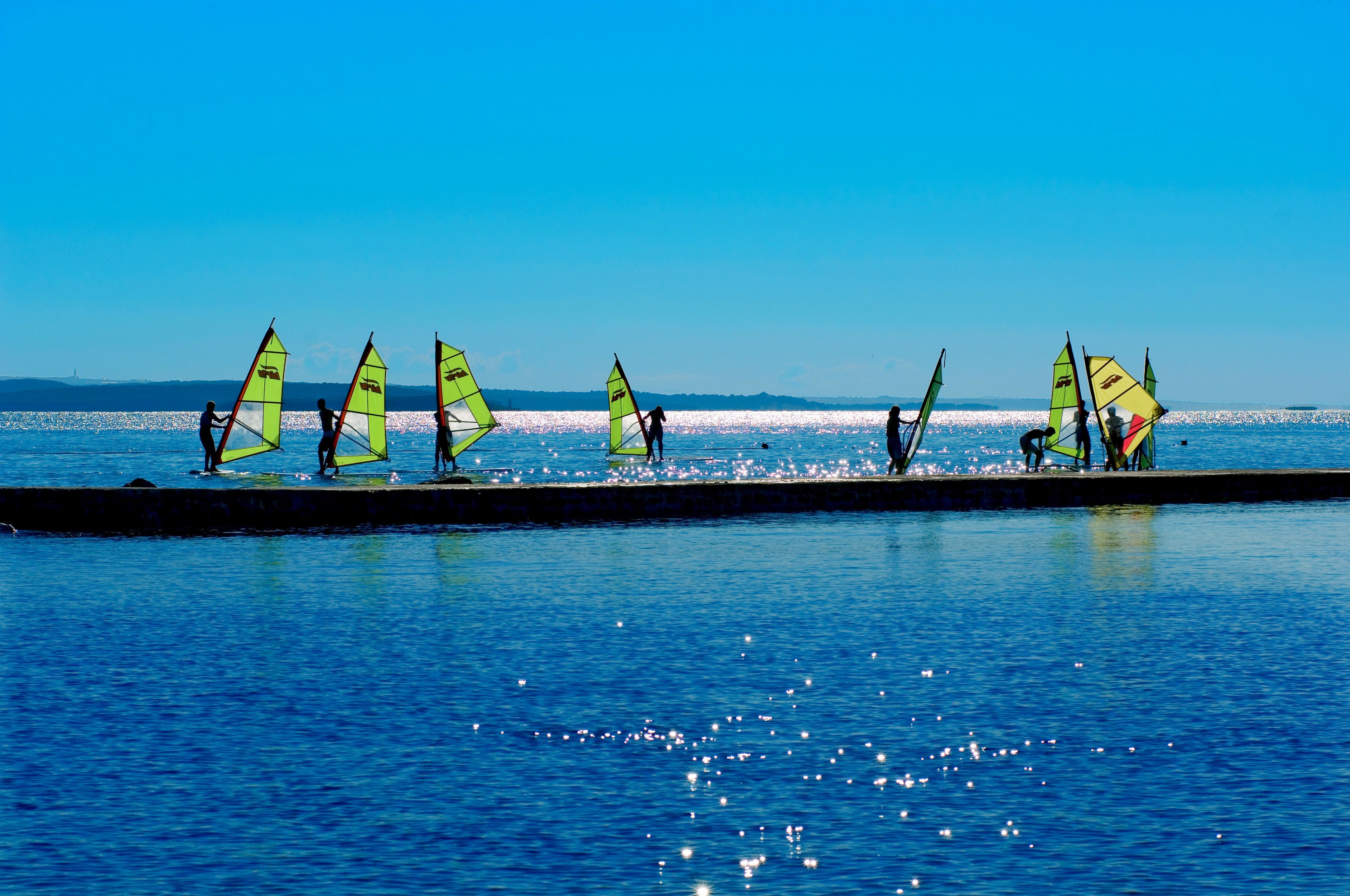 Ein Ufer mit Windsurfern.