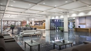 A spacious lobby with a reception desk, seating area, and a bar. - Eden Hotel by Maistra Collection (Rovinj)