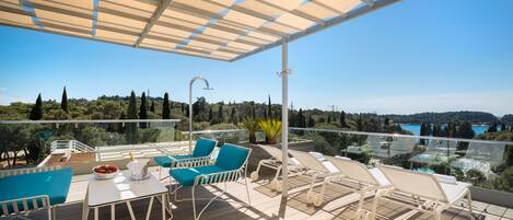 Una terraza con mobiliario exterior, una mesa con un frutero y vistas al paisaje.