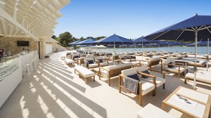 A sunlit outdoor seating area with lounge chairs and umbrellas, overlooking a body of water. - Eden Hotel by Maistra Collection (Rovinj)