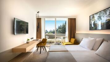 Una habitación de hotel moderna con cama, escritorio, silla y balcón con vistas a árboles y edificios.