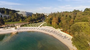 A cemetery with headstones arranged in rows, surrounded by trees and a body of water. - Eden Hotel by Maistra Collection (Rovinj)