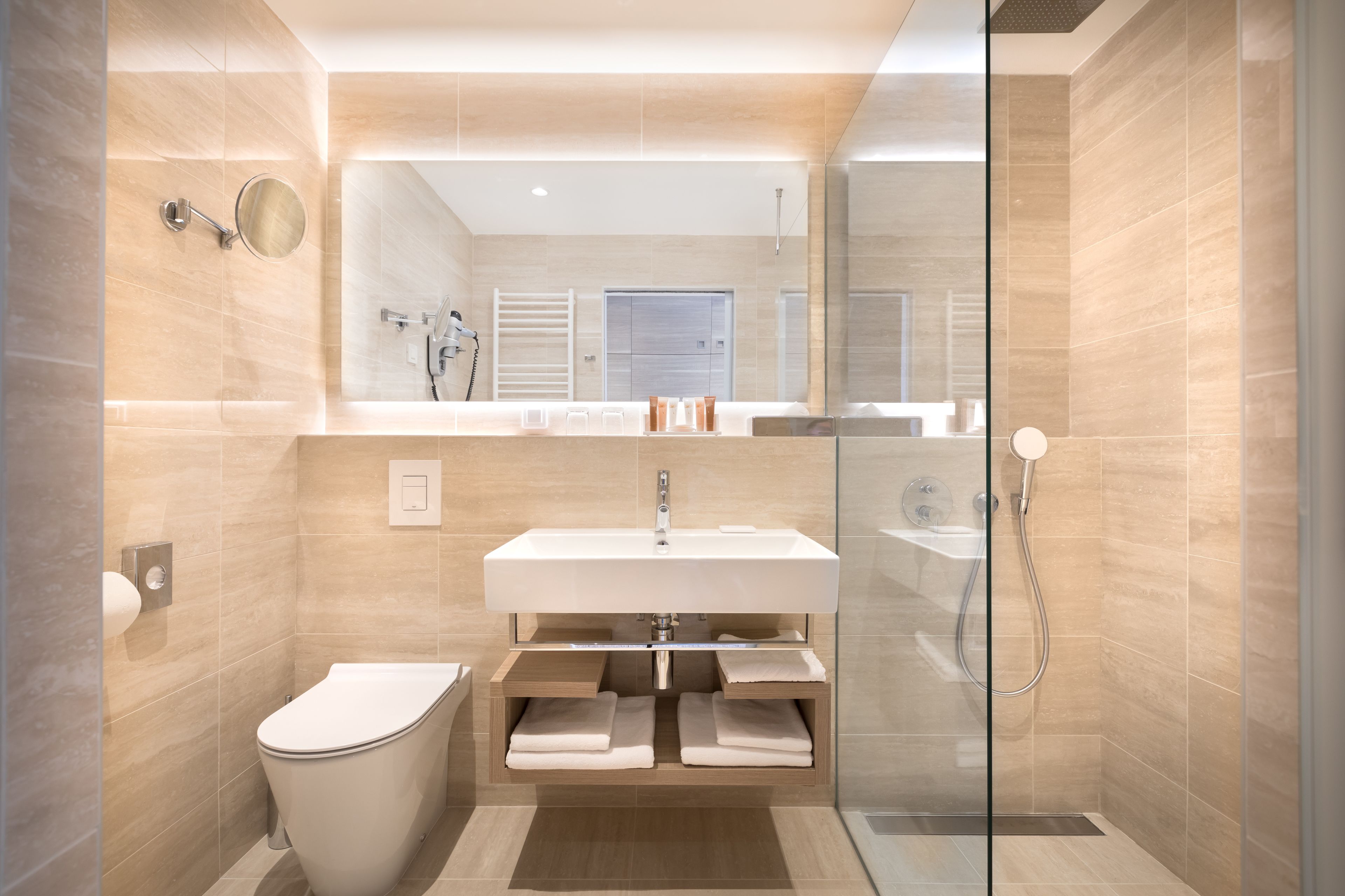 Een moderne badkamer met een glazen douchecabine, een witte wastafel en een toilet.