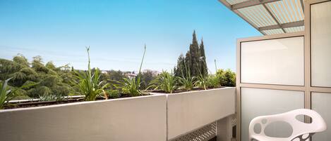 A balcony with a white chair, a small table, and a potted plant.
