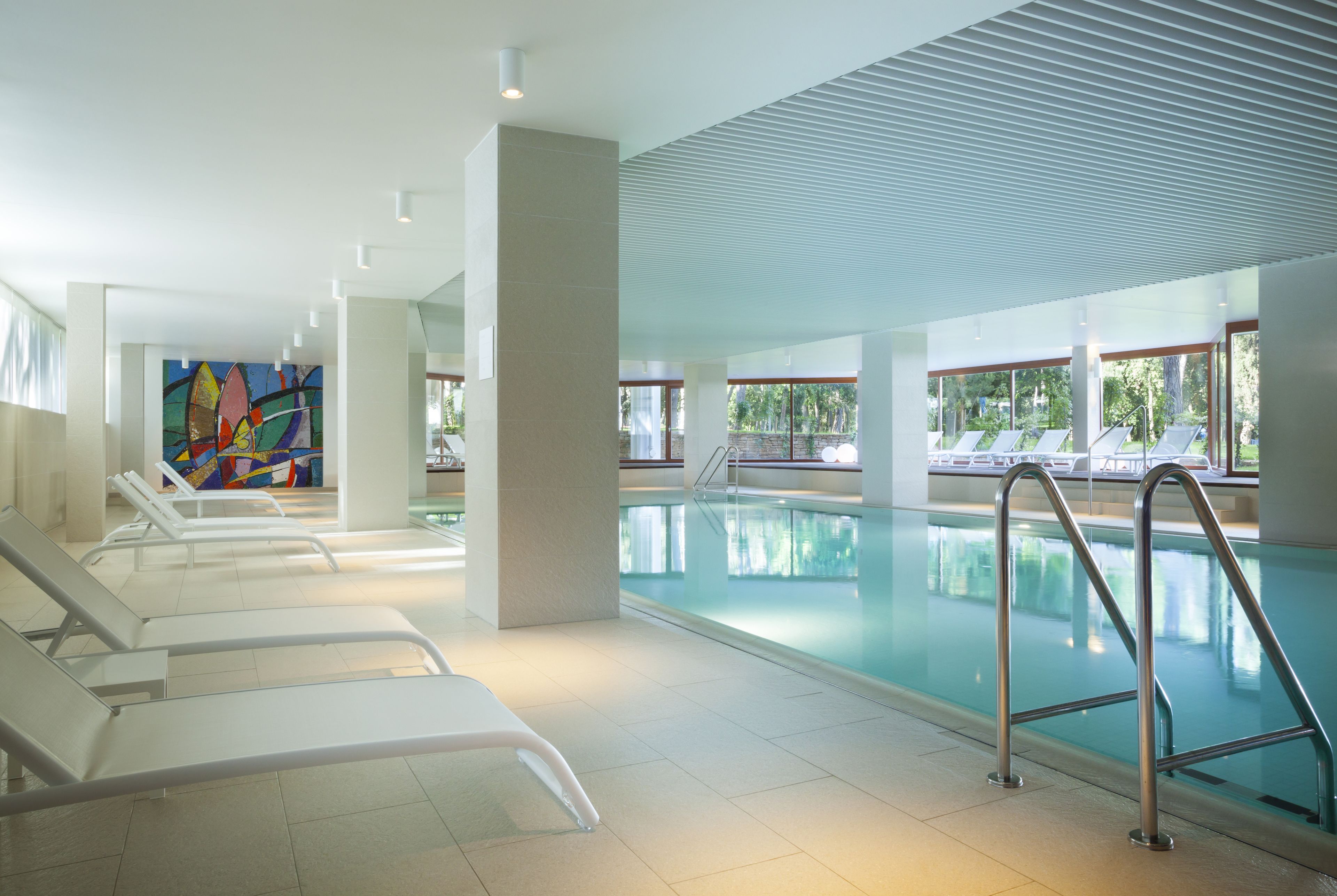 A swimming pool area with lounge chairs and a colorful mural.
