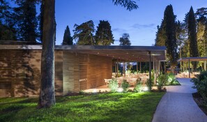 A modern outdoor patio area with wooden slatted walls, outdoor seating, and a pathway leading to a covered seating area. - Eden Hotel by Maistra Collection (Rovinj)