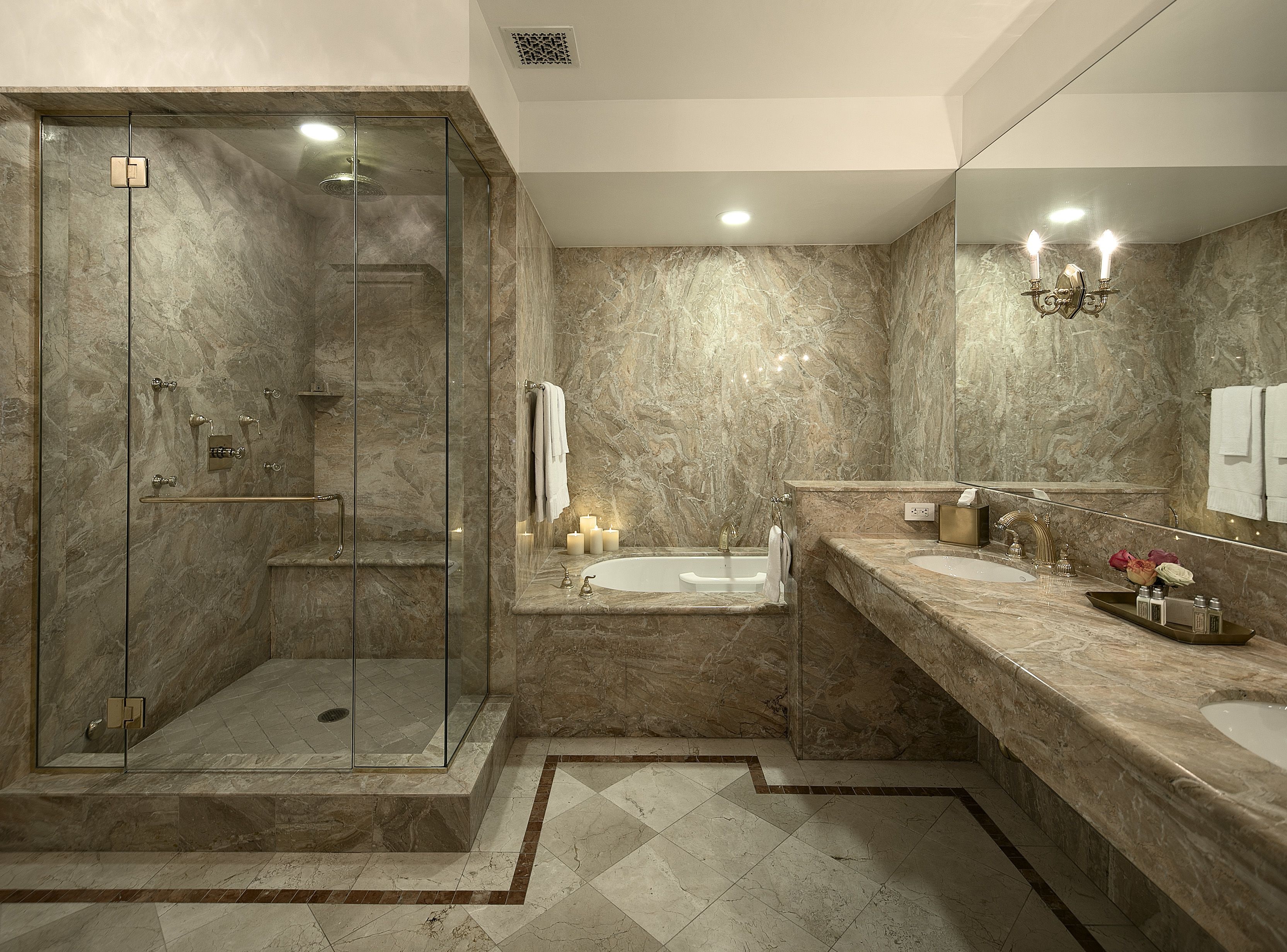 Une salle de bain moderne dotée d’une douche à parois de verre, d’une baignoire sur pieds et d’un meuble-lavabo en marbre avec un évier et un miroir.