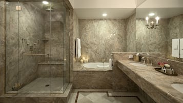 Un baño moderno con ducha envuelta en vidrio, una bañera independiente y un tocador de mármol con lavamanos y espejo.