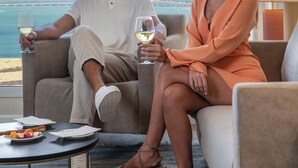 Un homme et une femme sont assis sur un canapé, face à la mer.