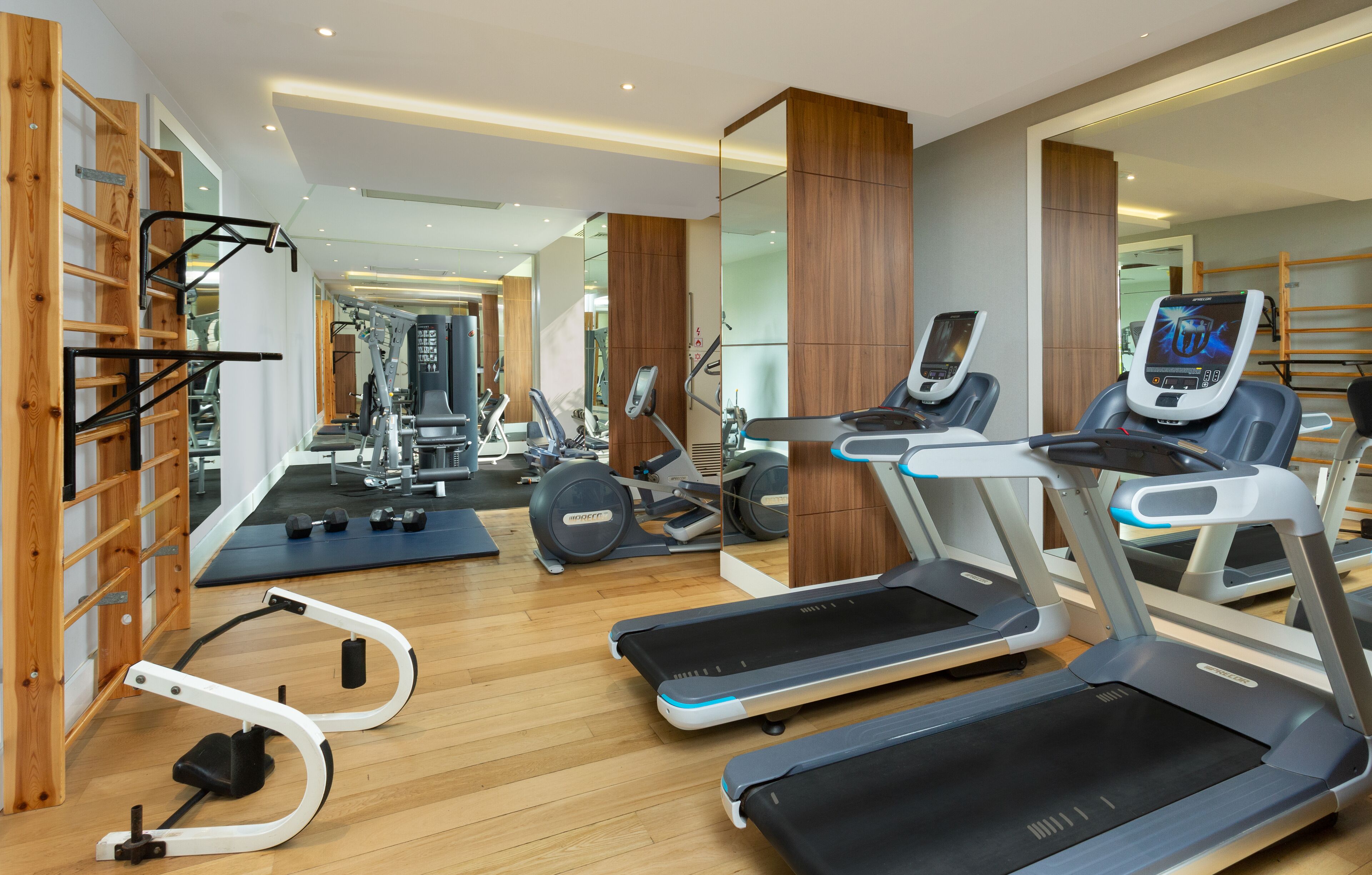 A modern gym with treadmills, ellipticals, and free weights.