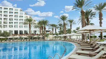 Una piscina techada, una piscina al aire libre, sombrillas