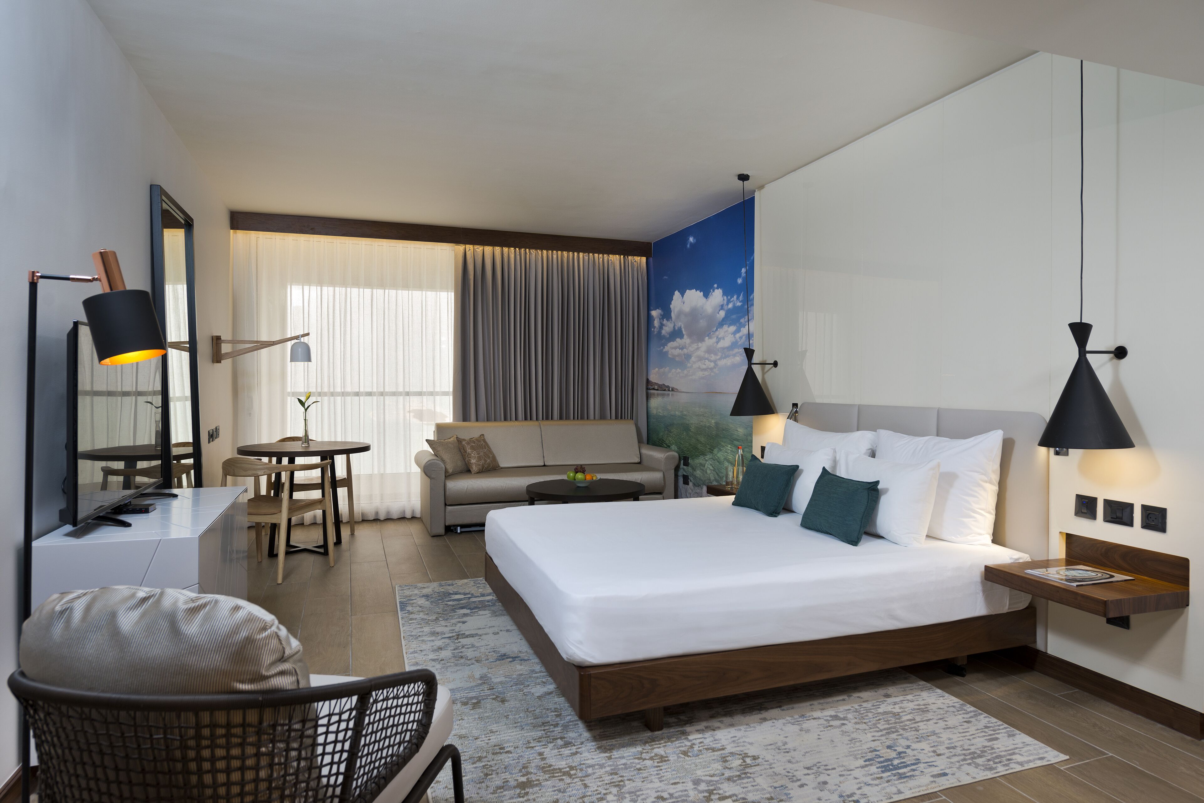 Une chambre d’hôtel moderne équipée d’un grand lit, d’un bureau, d’un canapé et d’un coin repas.