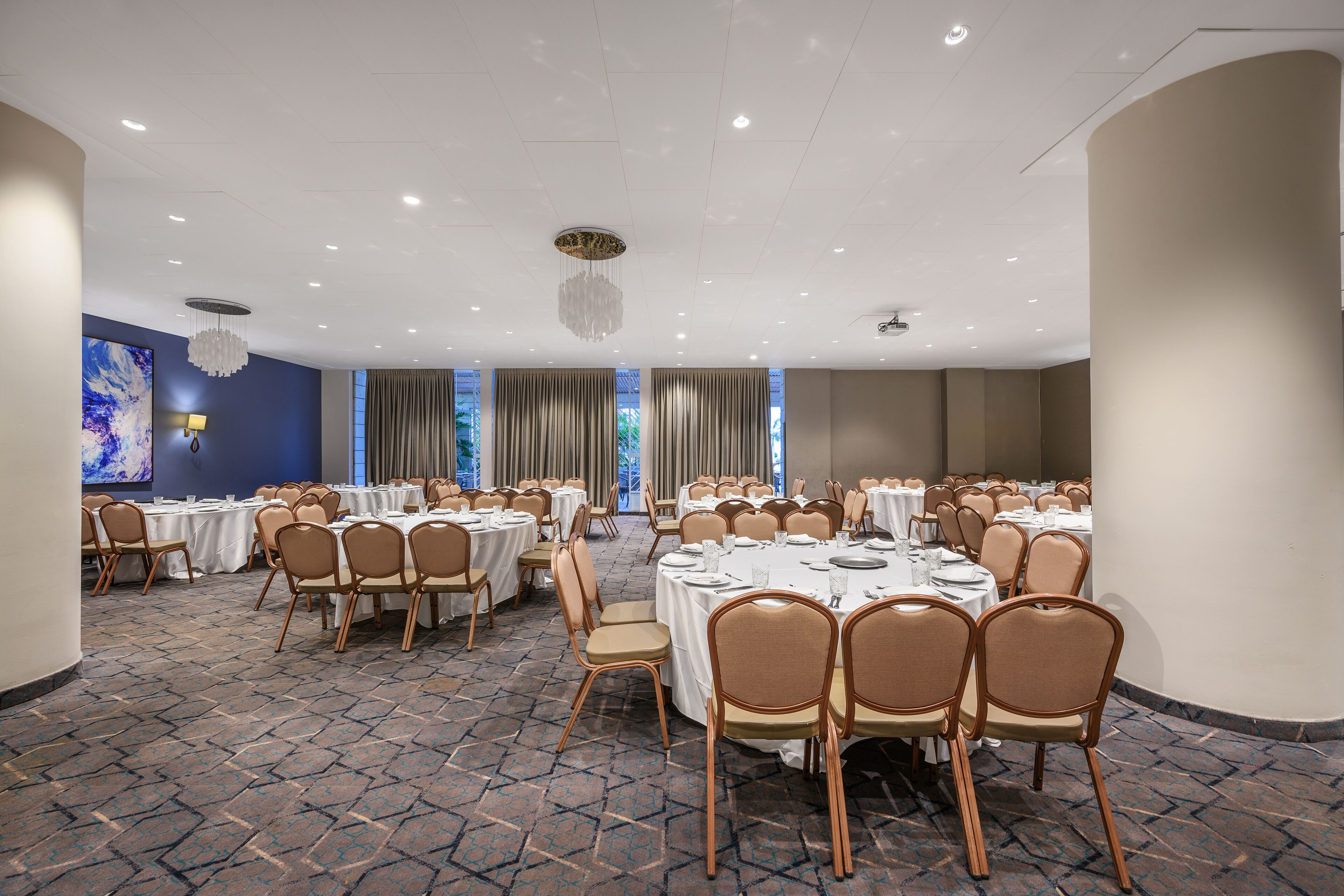 Une salle de conférence équipée de tables rondes, de chaises et d’un lustre.